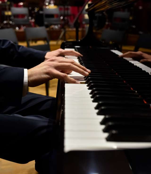 Male pianist playing classical music on a grand piano.